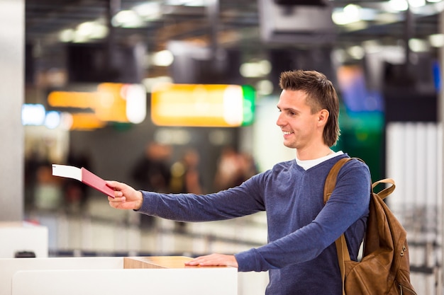 Young Man With Passports And Boarding Tickets At The Front Desk In