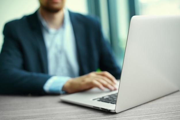Young man working with laptop, man's hands on notebook computer, business person at workplace Free Photo