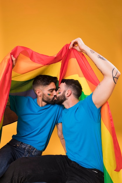 Young Men Kissing Under Lgbt Flag Free Photo