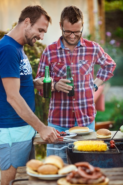 Young men roasting barbecue on grill in cottage ...