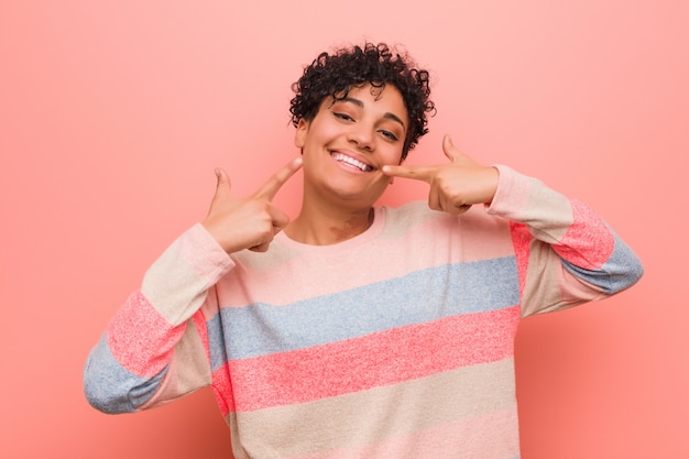 Young mixed african american teenager woman smiles, pointing fingers at mouth. Premium Photo