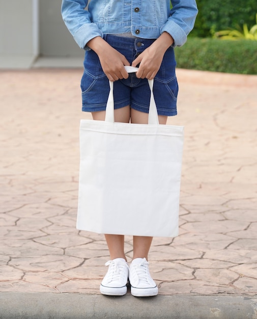 Young model holding white tote bag for mockup blank ...