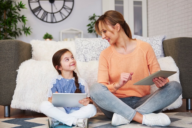 Young mom and her daughter using a tablet in living room Free Photo