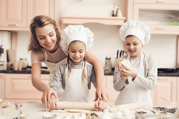 Premium Photo | Young mom teaches little daughter to roll a dough.