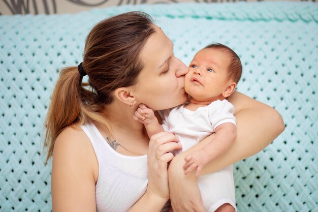 若い母親が生まれたばかりの赤ちゃんを優しく抱きしめる プレミアム写真