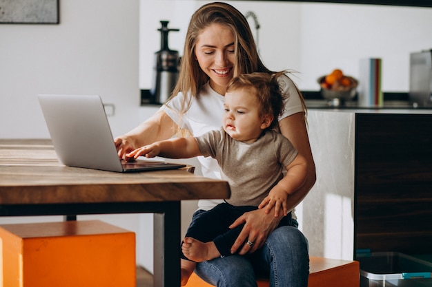 Young mother working from home on laptop with her little son Free Photo