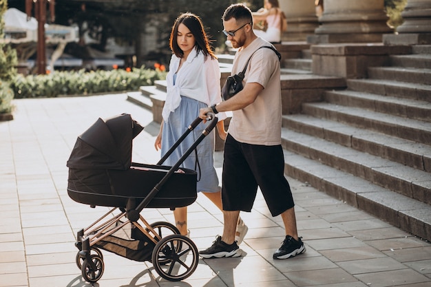 Free Photo | Young parents walking with their baby in a stroller