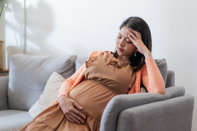 Premium Photo | Young pregnant asian woman has suffering from headache  sitting on sofa.