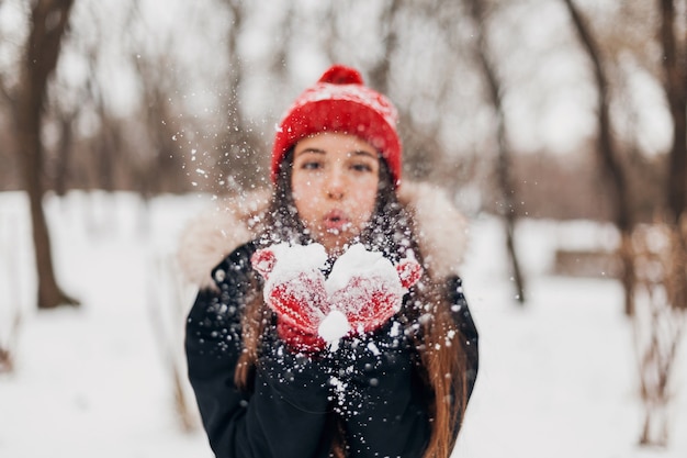 Free Photo | Young pretty smiling happy woman in red mittens and knitted  hat wearing winter coat, walking in park, blowing snow