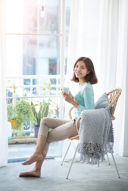 Premium Photo Young Pretty Woman Sitting At Opened Window Drinking Coffee And Looking Outside