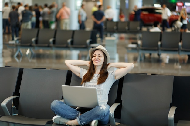 Premium Photo Young Relaxed Traveler Tourist Woman In Hat Sitting With Crossed Legs Working On 