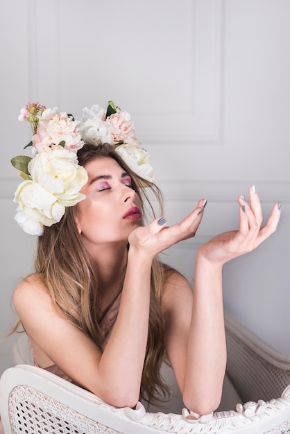 ソファの上の美しい花の花輪を持つ若いロマンチックな女性 無料の写真