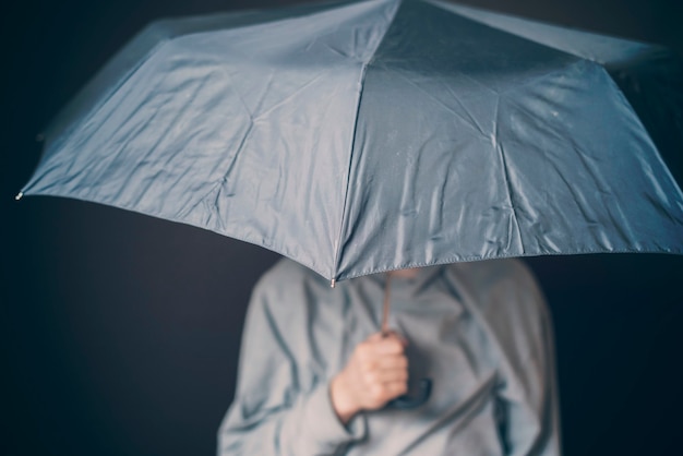 若い悲しい男は暗い背景bdの悪天候で傘を保持します プレミアム写真