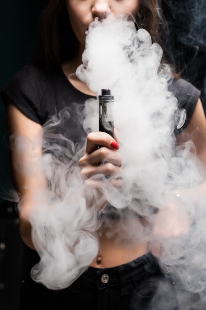 Free Photo Young Sexy Woman Is Vaping Smoking E Cigarette Cloud Of Vapor On The Black Wall 2660