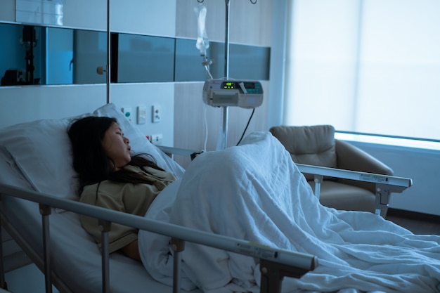 Young sick asian patient woman lying on bed in hospital ward Premium Photo