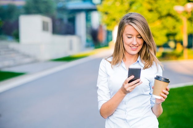 Young smart professional woman reading using phone. Female businesswoman reading news or texting sms on smartphone while drinking coffee on break from work. Free Photo Young smart professional woman reading using phone. Female businesswoman reading news or texting sms on smartphone while drinking coffee on break from work. Free Photo