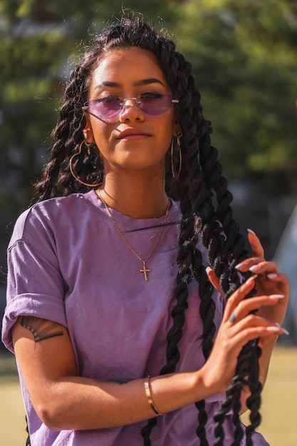 長い三つ編みを保持している紫色のシャツの若い笑顔浅黒い肌の女性 プレミアム写真