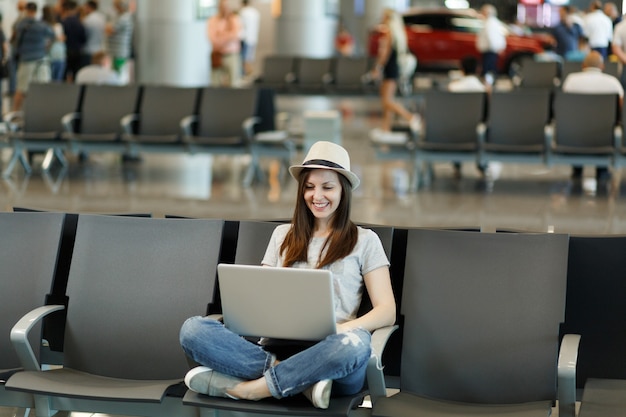 Free Photo Young Smiling Traveler Tourist Woman In Hat Sitting With Crossed Legs Working On 