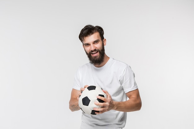 白い壁の前にボールを持つ若いサッカー選手 無料の写真