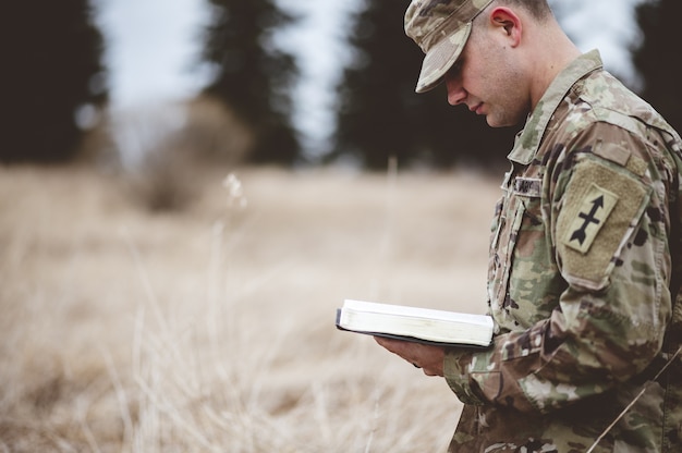 Free Photo | Young soldier reading a bible in a field