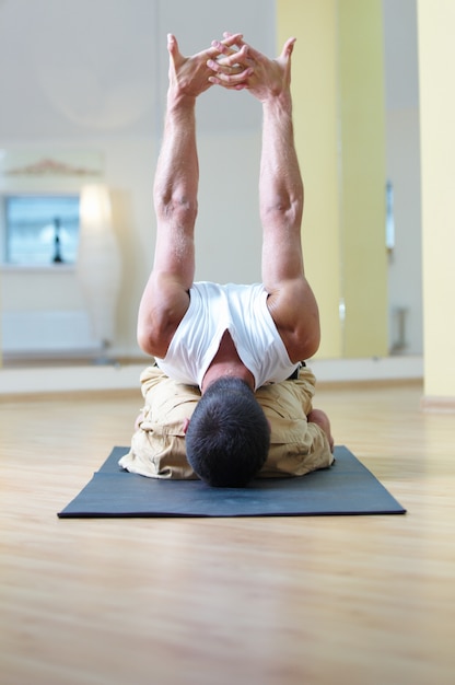 Premium Photo | A young strong man doing sitting yoga exercises. adho ...