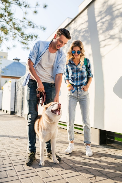 通りで犬を連れて歩いてスタイリッシュなカップル 男と女のハスキー犬と一緒に幸せ 無料の写真