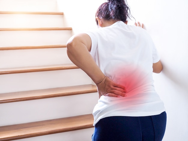 Premium Photo | Young thai asian woman suffering low back pain and waist  lumbar pain when walking up the stairs.