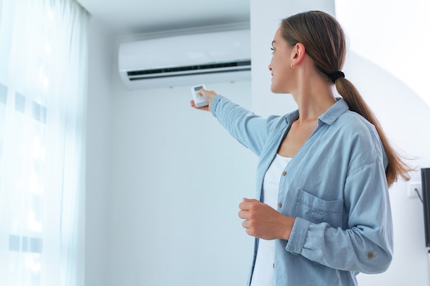 Young woman  adjusts the temperature of the air  conditioner  