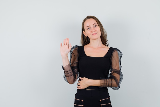 Free Photo | Young woman in black blouse showing goodbye gesture and