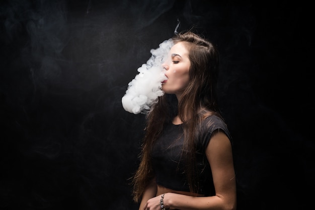 Free Photo | Young woman in black smokes an electronic cigarette on ...