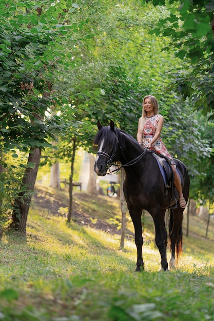 Free Photo | Young woman in a bright colorful dress riding a black horse