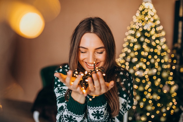 Free Photo | Young woman by the christmas tree with christmas glowing ...