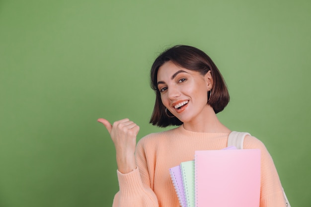 Young woman in casual peach sweater isolated on green olive color wall Free Photo