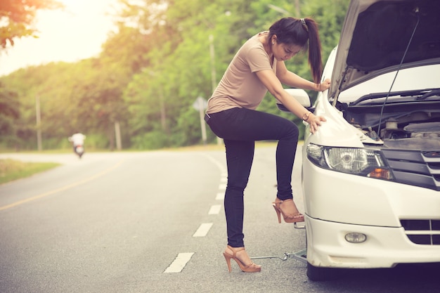 Premium Photo | Young woman changing flat tire in field