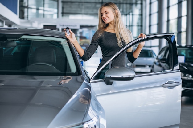 Free Photo | Young woman choosing a car in a car showroom