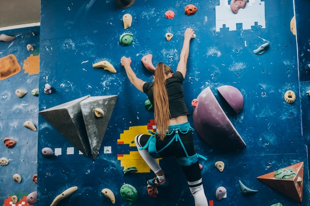 Free Photo | Young woman climbing a tall, indoor, man-made rock ...