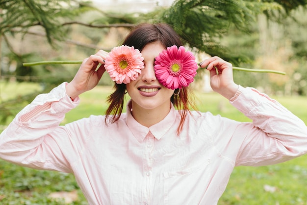 目の花を覆っていると笑顔の若い女性 無料の写真