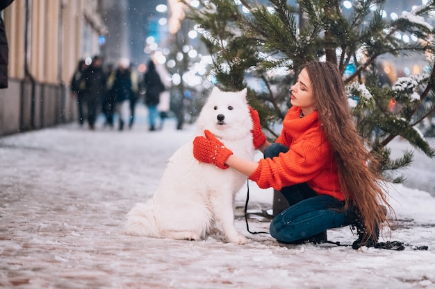 Free Photo | Young woman crouched beside a dog on a winter street