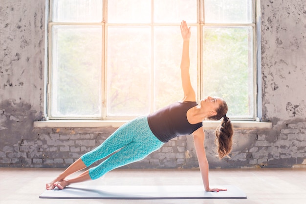 Young woman doing stretching exercise on blue background Free Photo