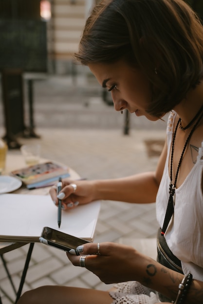 Free Photo Young woman draws at the sketchbook with a pencil outdoors