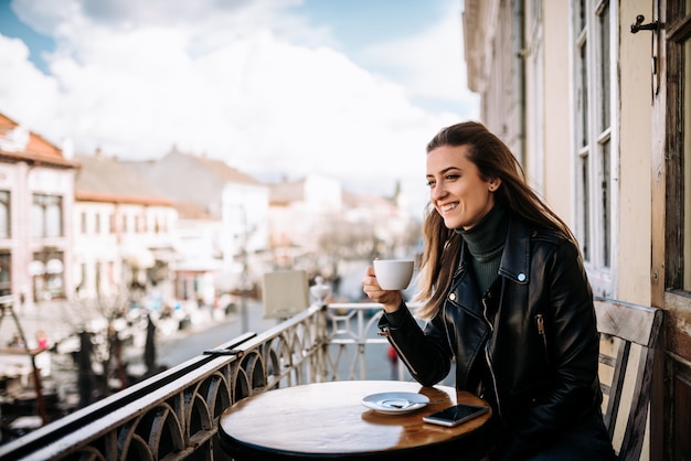 Premium Photo | Young woman drinking coffee on the balcony.