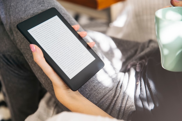 Young woman drinking coffee and using an ebook reader Premium Photo