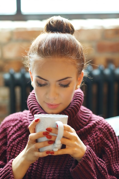 ソファーで熱いお茶を飲む若い女性 無料の写真