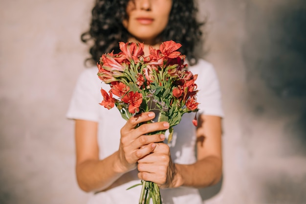 アルストロメリアの赤い花の花束を手で保持している若い女性 無料の写真