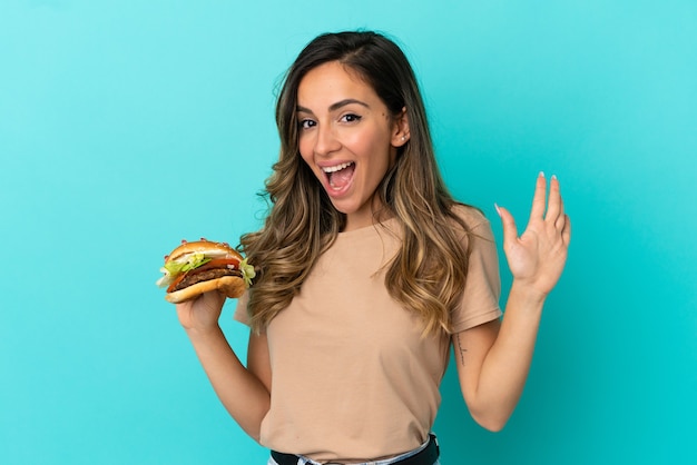 Premium Photo | Young woman holding a burger over isolated background ...