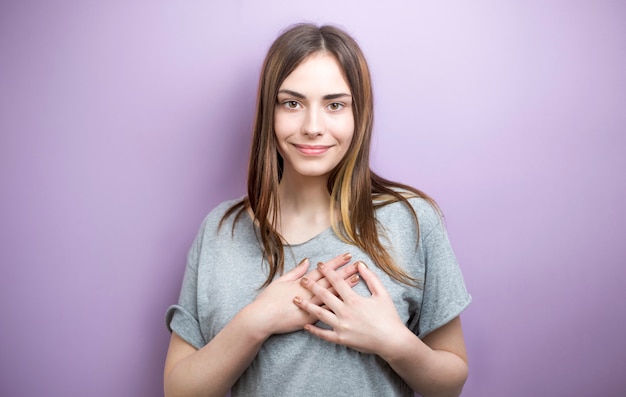 Premium Photo | Young woman holding hands on chest feeling pleased ...