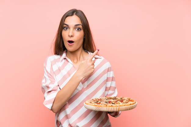 Premium Photo Young Woman Holding A Pizza Over Isolated Pink Wall