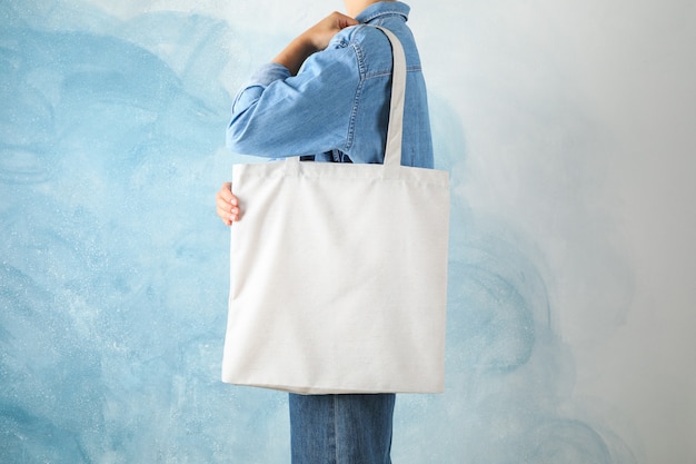 Premium Photo | Young woman holding tote bag against blue