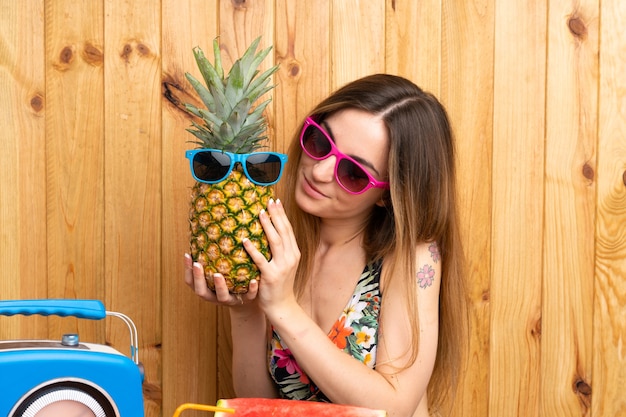 サングラスをかけたパイナップルを持った水着の若い女性 プレミアム写真