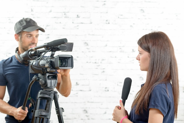 Premium Photo | Young woman journalist with a microphone and cameraman